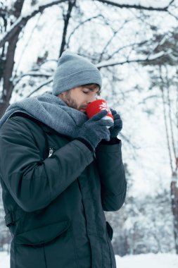 sıcak kahve kış parkta elinde tutan genç adam