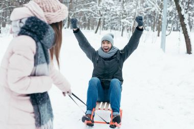 Genç çiftin birlikte kış gününde parkta sledging kısmi görünümü