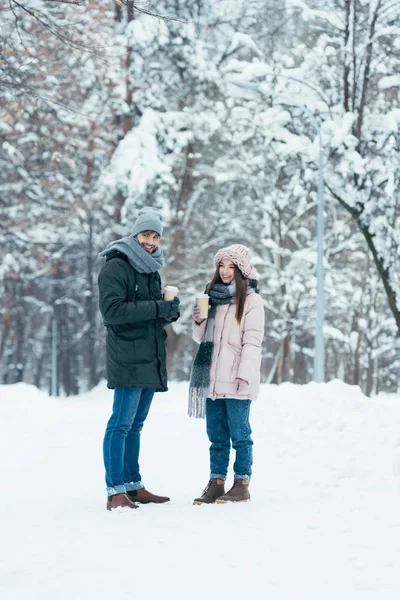 愉快的夫妇与咖啡去站立在雪公园 — 图库照片