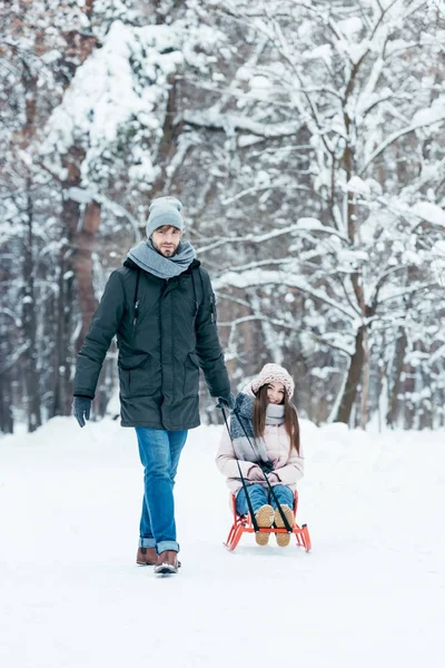 若いカップルが公園で冬の日に一緒にソリ — ストック写真