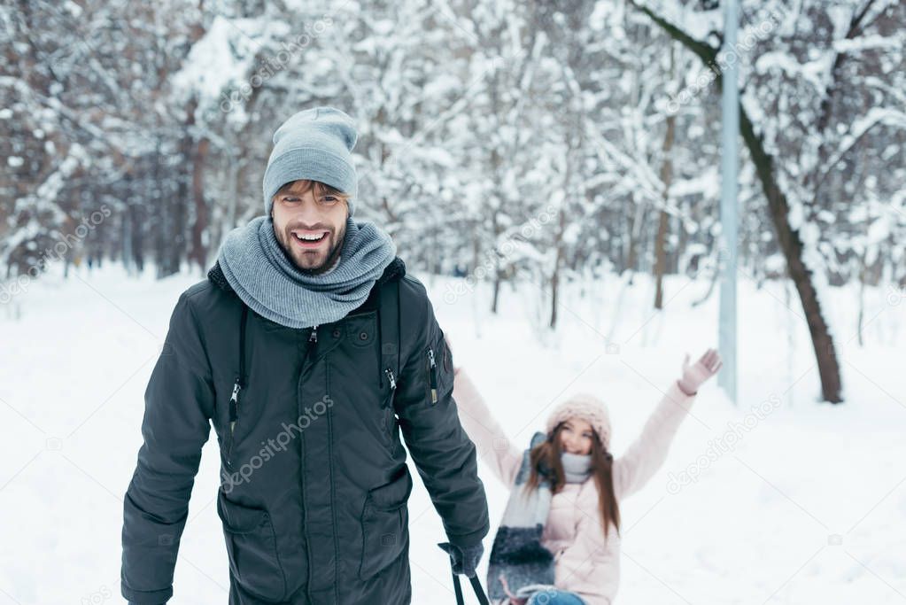 young couple sledging together on winter day in park