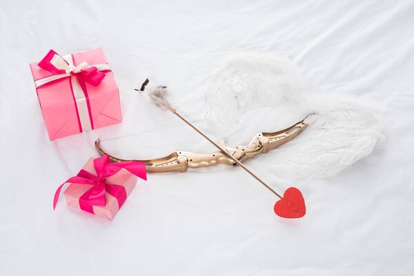 top view of presents, wings, bow and arrow on bed