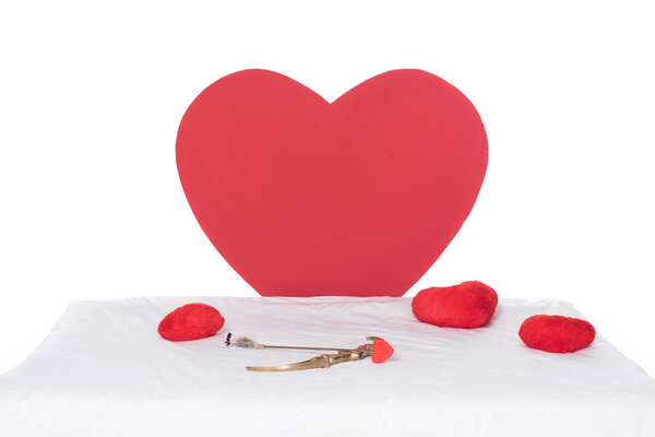 heart pillows, wings, bow and arrow on white bed