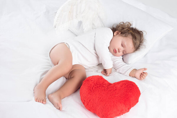 little baby with sleeping on bed with heart, isolated on white
