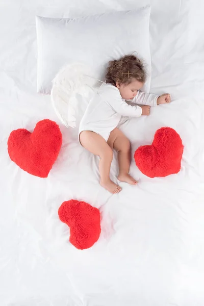 Pequeño Cupido Con Alas Acostado Cama Con Corazones Rojos — Foto de Stock