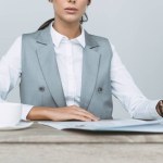 Cropped image of businesswoman reading newspaper isolated on gray