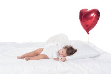 küçük melek kanatlı beyaz izole kalp balon ile yatakta yatmak