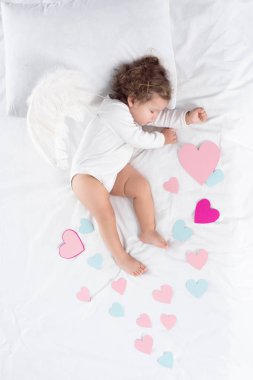 cupid with wings sleeping on bed with hearts clipart