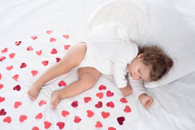 little cupid with wings sleeping on bed with red hearts clipart