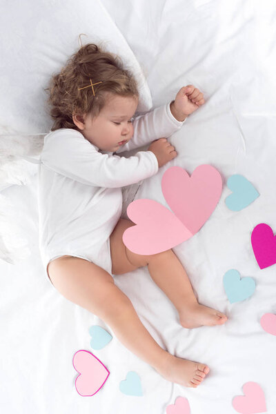 top view of little baby lying on bed with hearts