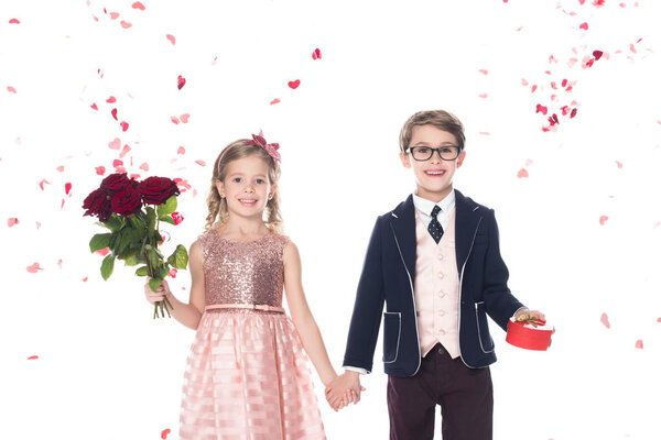 beautiful stylish kids with roses and heart shaped gift box holding hands and smiling at camera on white    