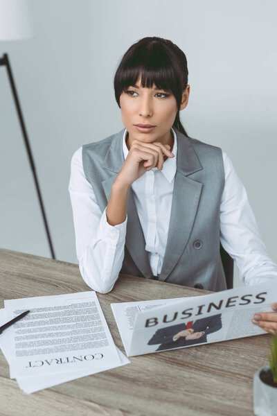 thoughtful businesswoman resting chin on hand isolated on gray