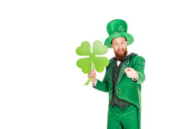 leprechaun in green suit pointing and holding clover, isolated on white