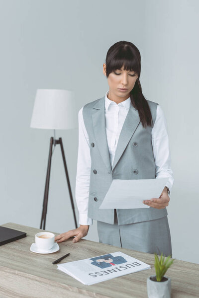 businesswoman looking at document isolated on gray