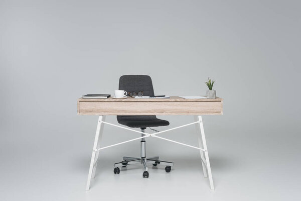 офисный стол с пустым стулом на сером
