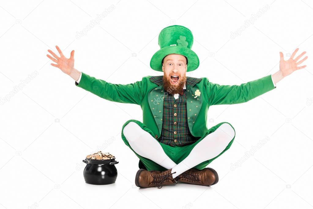 excited leprechaun gesturing and sitting at pot of gold, isolated on white 