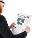 Plan recadré d'homme d'affaires barbu dans des lunettes de lecture journal isolé sur blanc