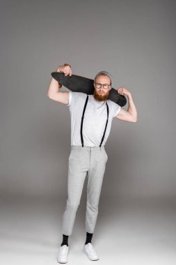 longboard omuzlarında tutarak ve kameraya gri görünümlü yakışıklı şık sakallı adam 
