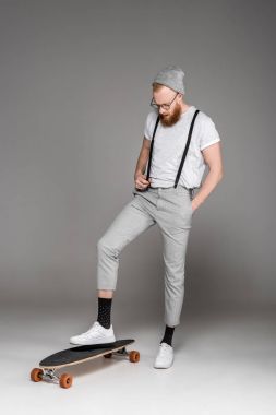 şık sakallı adam longboard üzerinde duran ve gri aşağı bakıyor