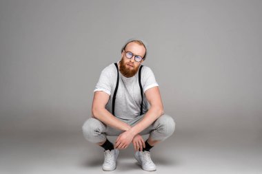 şapka ve gözlük çömelmiş ve kameraya gri görünümlü şık adam 