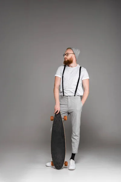 Handsome Stylish Bearded Man Standing Skateboard Looking Away Grey — Stock Photo, Image