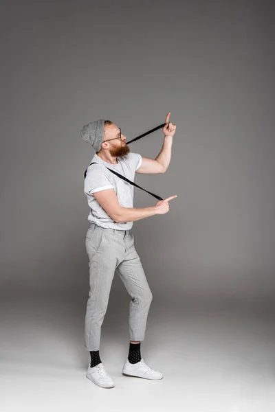 Stylish Bearded Man Playing Suspenders Pointing Fingers Grey — Free Stock Photo