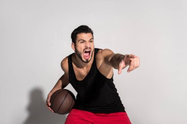 parmak ile işaret ve beyaz çığlık basketbol topu tutan agresif genç sporcu