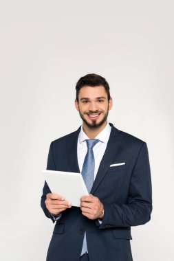 Dijital tablet tutarak ve gri izole kamera gülümseyen yakışıklı genç işadamı