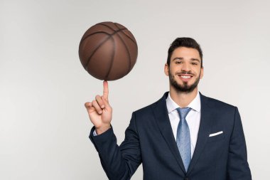 basketbol topu parmak üzerinde tutarak ve gri izole kamera gülümseyen genç işadamı  