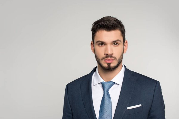 portrait of handsome young businessman looking at camera isolated on grey