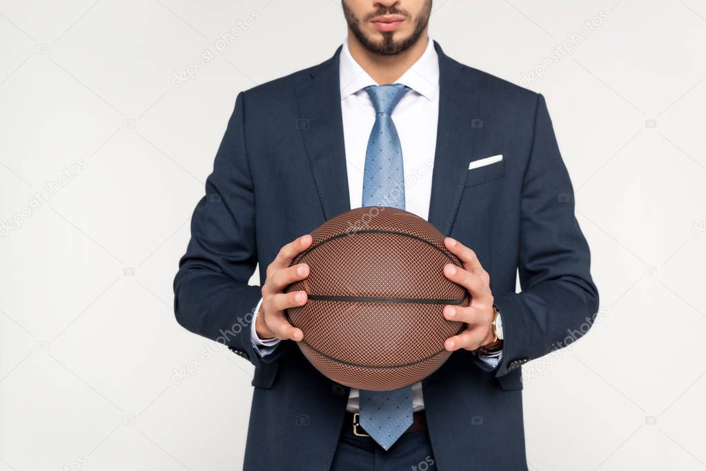 cropped shot of young businessman holding basketball ball isolated on grey