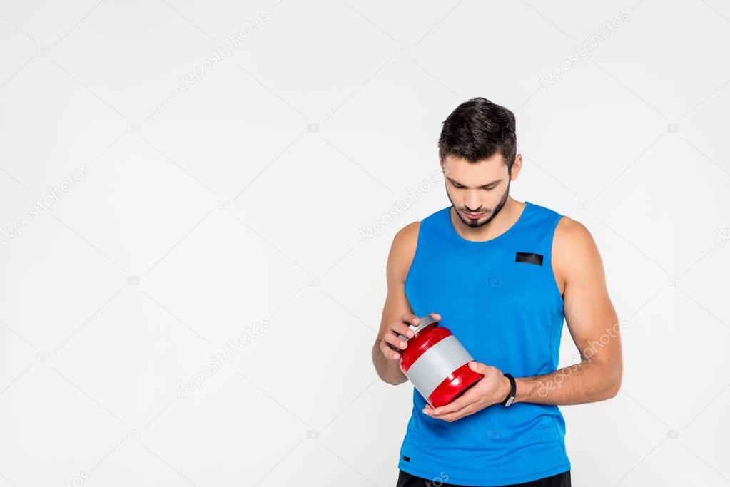 athletic young sportsman holding sport supplement jar isolated on white