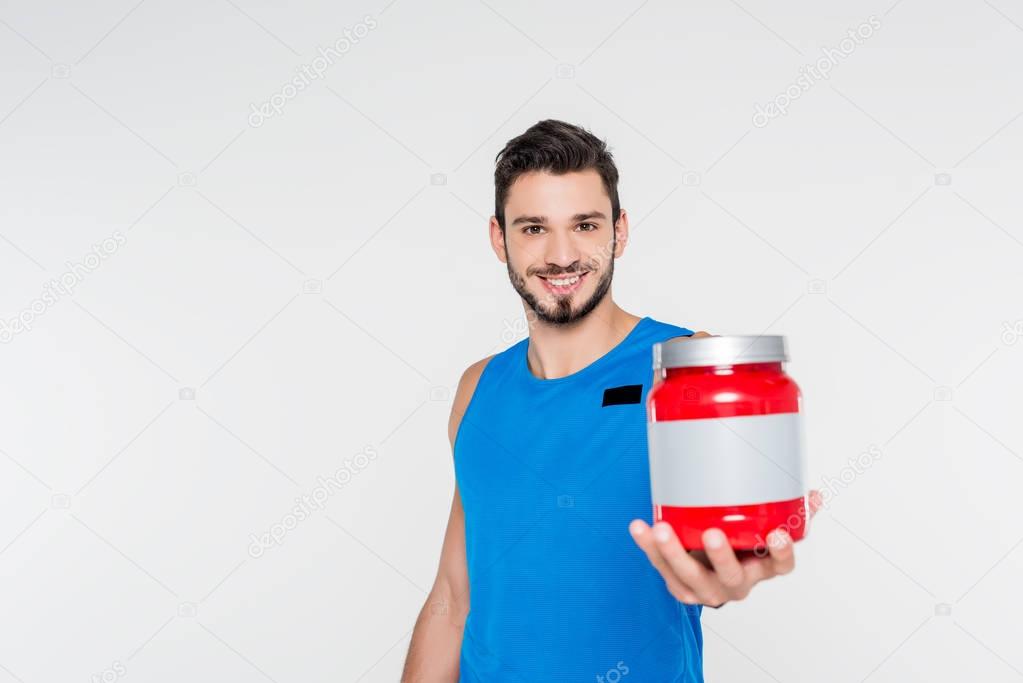 handsome young sportsman holding sport supplement jar isolated on white