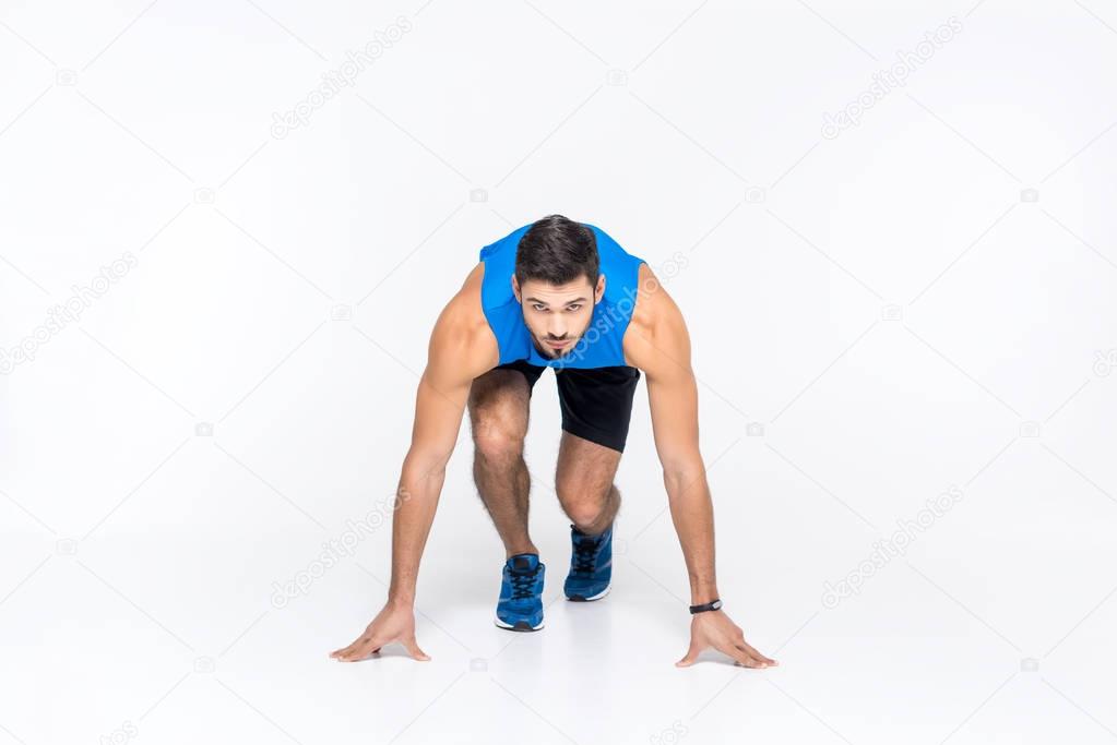 handsome young sprinter in start position isolated on white