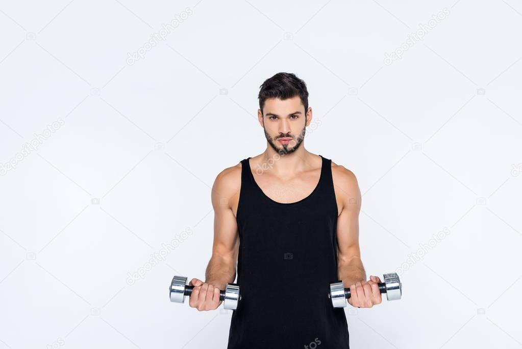 young man in sportswear working out with dumbbells isolated on white