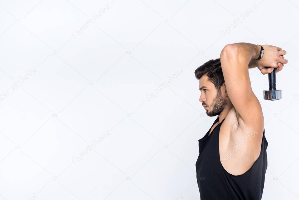 side view of young man working out with dumbbell isolated on white