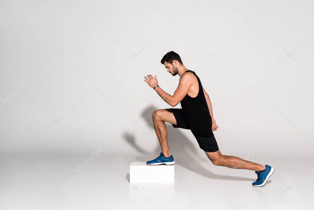 side view of athletic man doing step aerobics on block