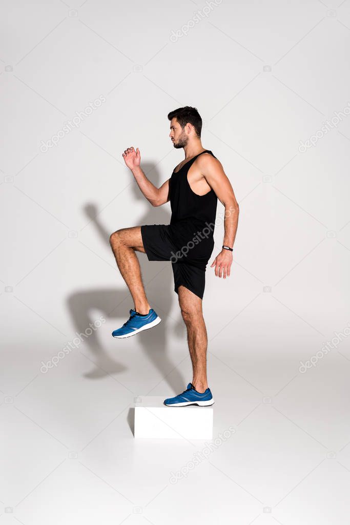 side view of sportive man doing step aerobics on block