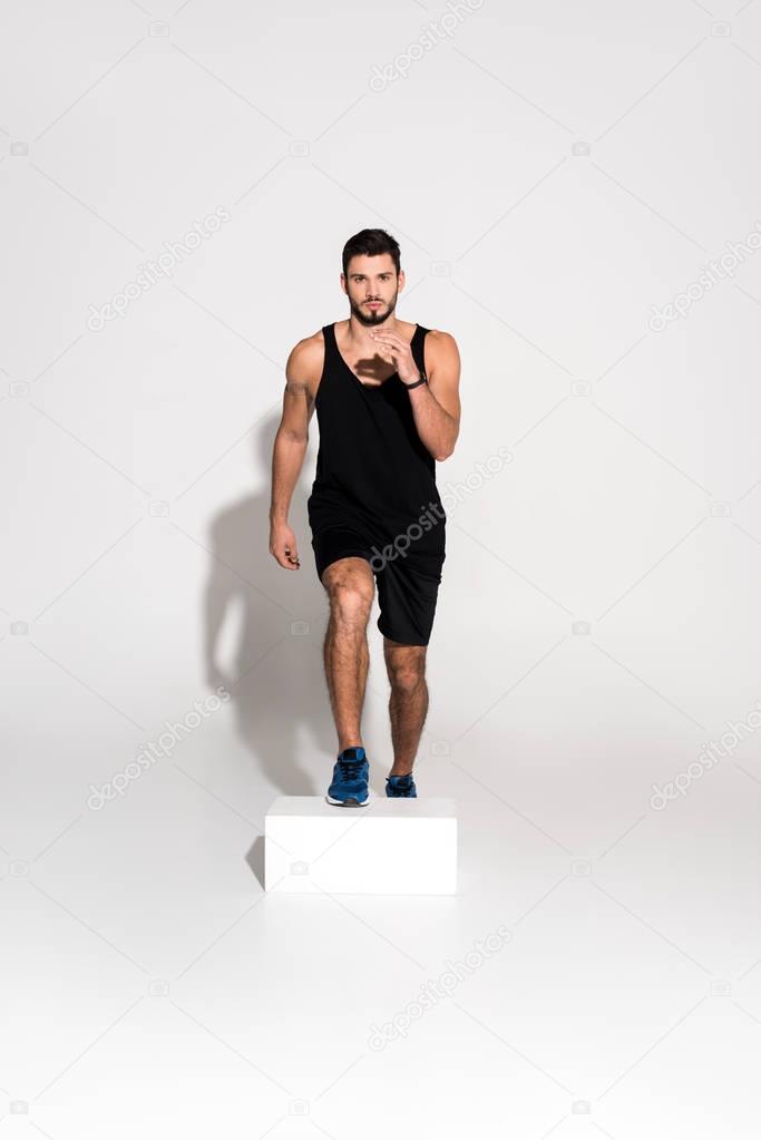 handsome young man doing step aerobics on block