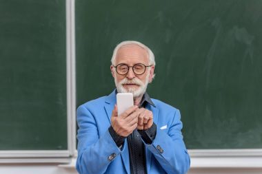 gri saç Profesör smartphone konferans odasında bakarak gülen