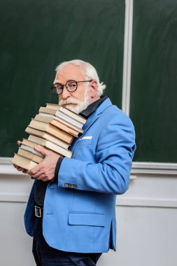 gri saç Profesör kitap yığını tutan 