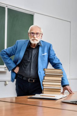 grey hair professor standing near stack of books clipart