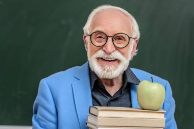 gri saç Profesör holding üst apple ile kitap yığını gülümseyen