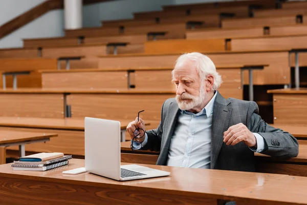 Grått Hår Professor Sitter Tomma Föreläsning Rum Och Tittar Laptop — Stockfoto