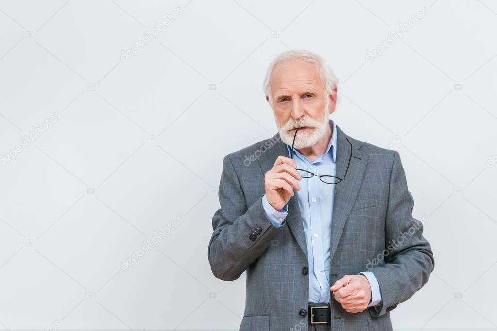 senior lecturer biting eyeglasses isolated on white