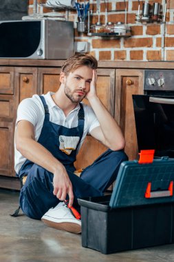 kırık fırın yakınındaki toolbox ile oturan üzgün genç ustabaşı 