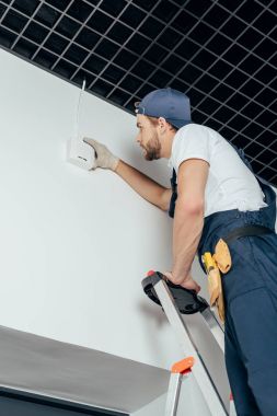 Genç elektrikçi ev alarmı sabitleme düşük açılı görünüş