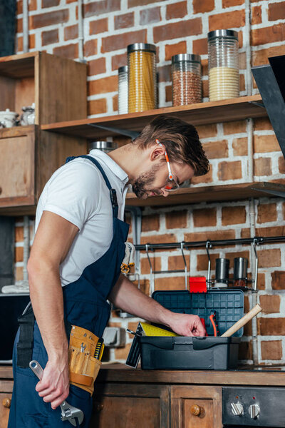 young repairman with toolbox working in kitchen