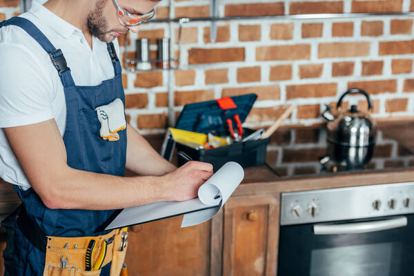 cropped shot of young repairman writing on clipboard