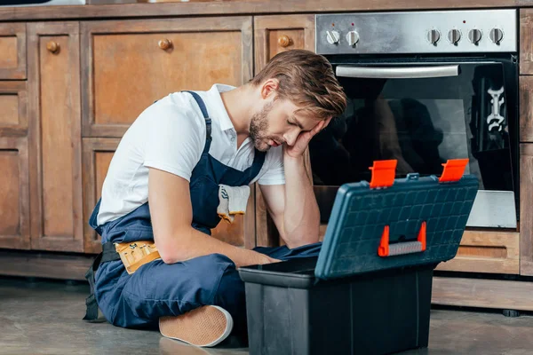 Tired Young Foreman Sitting Toolbox Broken Oven — Stock Photo, Image